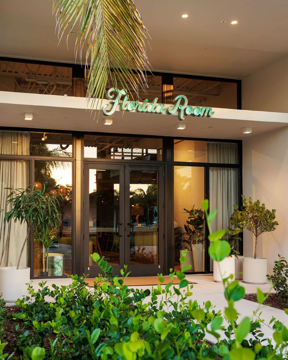 Entrance of Florida Room restaurant with neon sign and greenery in Fort Lauderdale