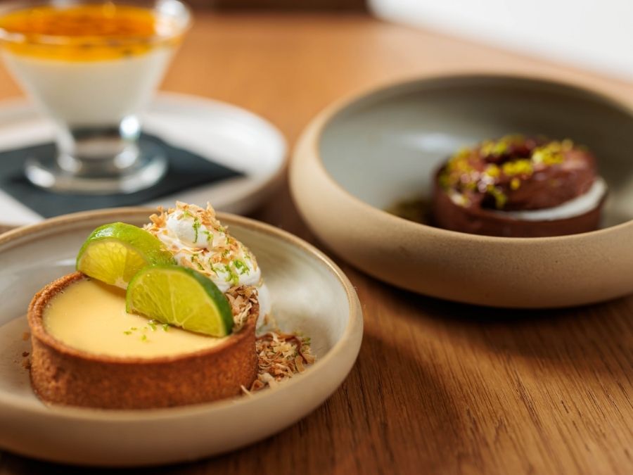 Key lime tart with whipped topping and lime slices alongside plated desserts at Florida Room