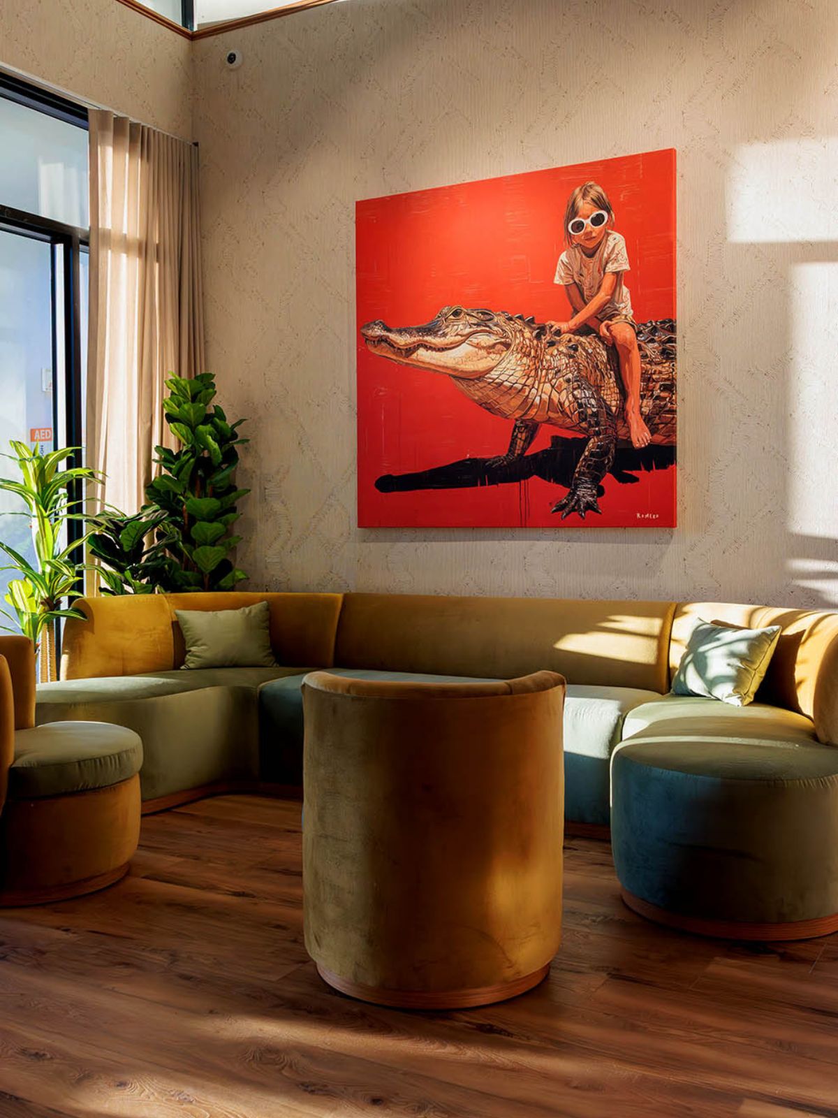 Lounge seating area at Florida Room with green velvet couches and bold red artwork