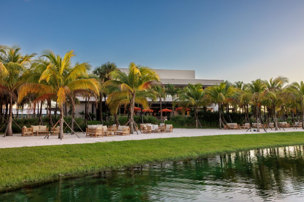 Exterior view of the Florida Room overlooking the lake with palm trees and outdoor seating in Fort Lauderdale.